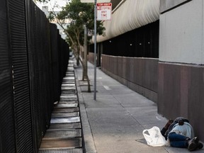 A person sleeps near a security fence setup around the Moscone convention center hosting the Asia-Pacific Economic Cooperation (APEC) leaders' week in San Francisco, California, on November 13, 2023.