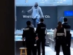 Person stand on a counter, appear to be holding a hammer with security guards