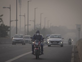 A motorcyclist drives wearing pollution mask amid smog in New Delhi, India, Tuesday, Nov. 7, 2023.
