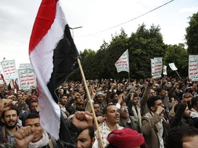 Houthi supporters chant slogans while holding signs.