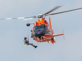 In this file photo, a U.S. Coast Guard MH-66 Dolphin lowers a crewman to the ground before recovering them during their performance at the London Air Show on Aug. 29, 2021 in London, Ont.