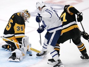 Penguins goaltender Tristan Jarry blocks a shot by Maple Leafs forward Calle Jarnkrok (centre) with Ryan Graves (right) defending during first period NHL action in Pittsburgh, Saturday, Nov. 25, 2023.