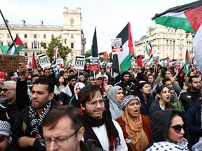People hold up placards and wave Palestinian flags in London's Parliament Square after taking part in a 'March For Palestine' on Oct. 28, 2023, to call for a ceasefire in the conflict between Israel and Hamas.