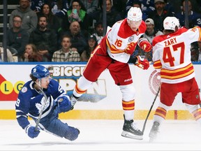 Nikita Zadorov, centre, of the Calgary Flames checks Tyler Bertuzzi, left, of the Toronto Maple Leafs during the third period at Scotiabank Arena on Nov. 10, 2023 in Toronto.