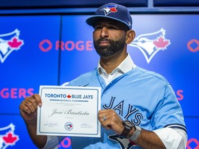 Jose Bautista poses with his contract during a press conference at the Rogers Centre in Toronto in Toronto, Ont. on Friday August 11, 2023. Bautista signed a one-day contract to officially retire as a member of the Toronto Blue Jays.