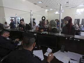 Palestinians with dual nationality register to cross to Egypt on the Gaza Strip side of the border crossing in Rafah on Thursday, Nov. 2, 2023.