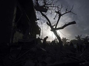 Palestinians inspect the damage of a destroyed house following Israeli airstrikes in the town of Khan Younis, southern Gaza Strip, Wednesday, Nov. 22, 2023.