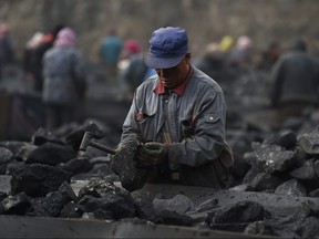 This file photo taken on Nov. 20, 2015 shows a worker sorting coal on a conveyer belt, near a coal mine at Datong in northern China's Shanxi province.
