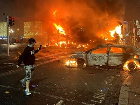 Flames rise from a car and a bus, set alight at the junction of Bachelors Walk and the O'Connell Bridge, in Dublin on Nov. 23, 2023, as people took to the streets in protest following the stabbings earlier in the day.