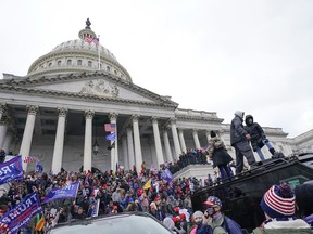 Rioters loyal to president Donald Trump stand on vehicles and the steps of the U.S. Capitol.
