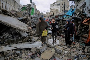 Palestinians walk amid debris of buildings hit in Israeli strikes, near Al-Zawiya market in Gaza City on Nov. 27, 2023, on the fourth day of a truce in fighting between Israel and Hamas.