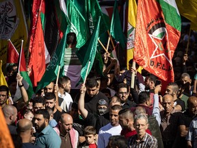 Palestinians lift flags of Hamas and other groups as they demonstrate in Ramallah in the occupied West Bank on Nov. 10, 2023, amid ongoing battles between Israel and the Hamas movement in the Gaza Strip.