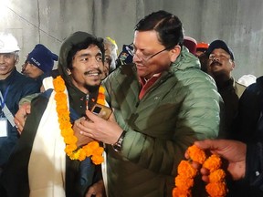 This handout picture released by Uttarakhand's Department of Information and Public Relation (DIPR) and taken on Nov. 28, 2023, shows a contruction worker (left) interacting with Chief minister of Uttarakhand Pushkar Singh Dhami (right) following his rescue from inside the under construction Silkyara tunnel during a rescue operation for trapped workers after a section of the tunnel collapsed in the Uttarkashi district of India's Uttarakhand state