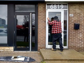 A man looks through a glass door into a Jewish community centre on Decarie Blvd. that was firebombed overnight