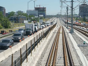 Traffic is seen on a road as a train rolls along the track in between lanes of a freeway during a media tour of the Reseau express metropolitain (REM) in Brossard, Que. on Thursday, June 10, 2021.