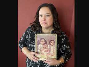 Sheri Wildman holds a photo of herself, at about six months of age, Jocelyn Wildman, almost two, and their older half-sister Tricia Paquette, then six years old.