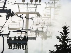 Skiers and snowboarders ride the first chairs on opening day at Canada Olympic Park in Calgary, Alta., on Friday, Nov. 24, 2023.