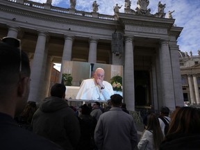 A giant screen broadcasts Pope Francis coughing during the Angelus noon prayer, from the chapel of the hotel at the Vatican grounds where he lives, Sunday, Nov. 26, 2023.