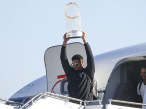 Texas Rangers' Marcus Semien hoists the Commissioner's Trophy next to pitcher José Leclerc upon the arrival of the baseball team at Dallas Love Field on Thursday, Nov. 2, 2023, in Dallas, the day after their World Series win over the Arizona Diamondbacks.