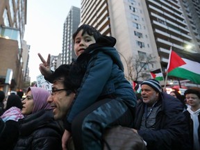 A youngster flashes a peace sign as people take part in a demonstration in support of the Palestinian people in downtown Montreal on Oct. 10, 2023.