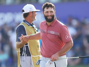 Jon Rahm of Spain shakes hands with his caddie, Adam Hayes (obscured), on the 18th green during Day Four of the DP World Tour Championship on the Earth Course at Jumeirah Golf Estates on November 19, 2023 in Dubai, United Arab Emirates.