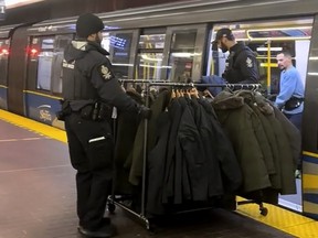 A still from a handout video posted on social media shows Metro Vancouver Transit Police on Monday, Dec. 25, 2023, removing a rolling rack of coats from a SkyTrain car.