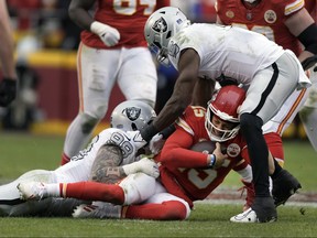Kansas City Chiefs quarterback Patrick Mahomes (15) is stopped by Las Vegas Raiders defensive end Maxx Crosby (98) and linebacker Divine Deablo (5) during the second half of an NFL football game Monday, Dec. 25, 2023, in Kansas City, Mo.