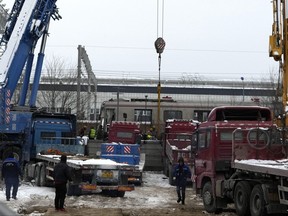 A crane is seen operating near the train carriages at the site of a train collision on the western district in Beijing, Friday, Dec. 15, 2023.