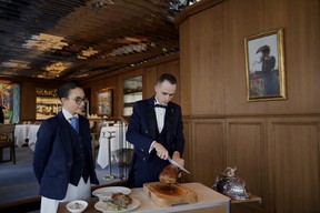 A waiter cuts a duck cooked at La Tour d'Argent restaurant in Paris, Wednesday, Dec. 13, 2023. (AP Photo/Christophe Ena)