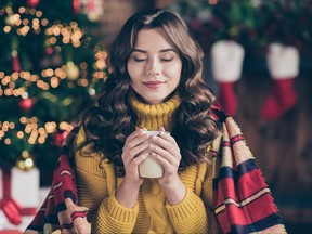 Close up photo of cheerful fun nice positive cute charming girl sensing nice smell of drink wearing yellow pullover sitting in plaid enjoying her carefree leisure with cup of tea
