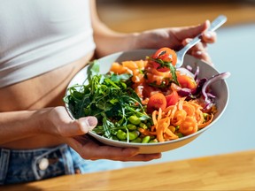 Fitness woman eating a healthy poke bowl in the kitchen at home.