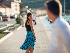 A man on the street looks at a young attractive woman.