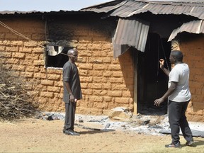 People stand in front of a burnt house following an attacked by gunmen in Bokkos, north central Nigeria, Tuesday, Dec. 26, 2023.