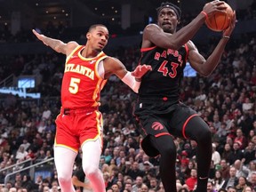 Raptors forward Pascal Siakam (right) collects a pass as Hawks guard Dejounte Murray (left) defends during first half NBA action in Toronto, Friday, Dec. 15, 2023.