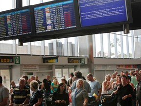 In this file photo, passengers look at information screens displaying cancelled flights at the Reina Sofial airport on the touristic Spanish Canary Island of Tenerife on May 11, 2010.
