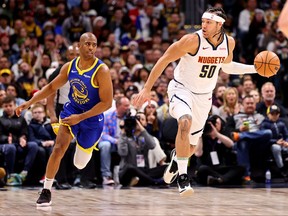 Aaron Gordon of the Denver Nuggets dribbles past Chris Paul of the Golden State Warriors during the first half at Ball Arena on Dec. 25, 2023 in Denver, Col.