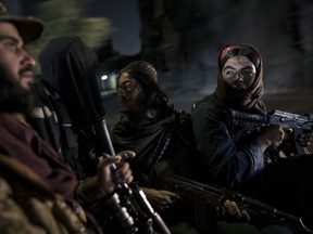 Taliban fighters ride in the back of a vehicle during a night patrol in Kabul, Afghanistan, Sept. 12, 2021. Taliban officials are sending Afghan women to prison to protect them from gender-based violence, according to a U.N. report published Thursday, Dec. 14, 2023.