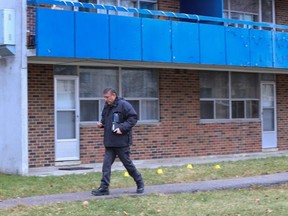 A Toronto Police officer walks by markers on Dec. 11, 2023, after two boys were found without vital signs in a Scarborough apartment. Their mother underwent surgery after plummeting Sunday from her sixth-floor apartment. The boys were pronounced dead in hospital. The building is located at 5 Glamorgan Ave. in the Kennedy-Ellesmere Rds. area.