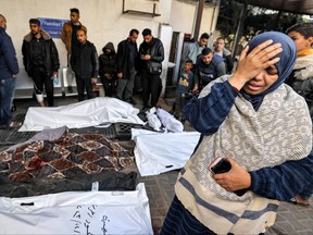 A woman mourns by the bagged bodies of Palestinians who were killed overnight during Israeli bombardment, at a hospital in Rafah in the southern Gaza Strip on Dec. 19, 2023 amid continuing battles between Israel and the militant group Hamas.