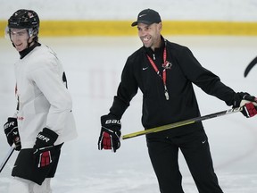 Canada's head coach Alan Letang, right, laughs with forward Fraser Minten at practice during Canadian World Juniors selection camp in Oakville, Ont., on Monday, Dec. 11, 2023.