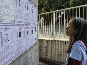 A pedestrian looks at the police reward notices for the arrest warrants issued for eight pro-democracy activists living in the United States, Britain, Canada and Australia for alleged national security offences in Hong Kong, Friday, July 14, 2023.
