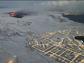 The evacuated Icelandic town of Grindavik (right) is seen as smoke billow and lava is thrown into the air from a fissure during a volcanic eruption on the Reykjanes peninsula 3 km north of Grindavik, western Iceland on Dec. 19, 2023.