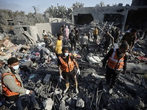 Palestinians inspect the damage of a destroyed house following Israeli airstrikes on Khan Younis, Southern Gaza Strip, Sunday, Dec. 31, 2023.