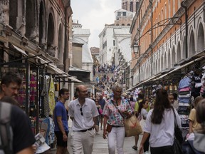 Tourists walk in a crowded street in Venice