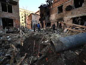 Local residents inspect damages outside an apartment building after the overnight Russian drones attack in Kharkiv, Dec. 31, 2023, amid the Russian invasion of Ukraine.