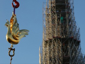The new golden rooster containing relics is lifted by crane to be installed atop the spire of Notre Dame cathedral as part of its reconstruction, in central Paris on Dec. 16, 2023.