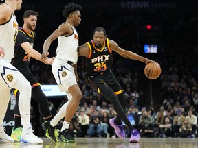 Phoenix Suns forward Kevin Durant (35) drives as Denver Nuggets forward Peyton Watson defends during the first half of an NBA basketball game, Friday, Dec. 1, 2023, in Phoenix.