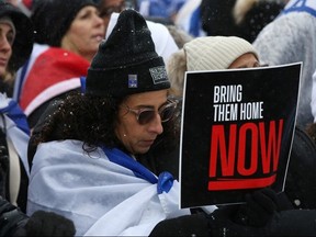 A woman bows her head while holding a sign during a rally in support of the Jewish community, on Parliament Hill in Ottawa, on Dec. 4, 2023.