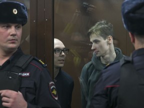 Artyom Kamardin, left, and Yegor Shtovba, right, stand behind a glass in a cage in a courtroom in Moscow, Russia, Thursday, Dec. 28, 2023. Artyom Kamardin was given a 7-year prison sentence Thursday for reciting verses against Russia's war in Ukraine, a tough punishment that comes during a relentless Kremlin crackdown on dissent. Yegor Shtovba, who participated in the event and recited Kamardin's verses, was sentenced to 5 1/2 years on the same charges. (AP Photo)
