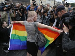 FILE - A gay rights activist stands with a rainbow flag, in front of journalists, during a protesting picket at Dvortsovaya (Palace) Square in St.Petersburg, Russia, Sunday, Aug. 2, 2015. Russia's Supreme Court on Thursday, Nov. 30, 2023, effectively outlawed LGBTQ+ activism, in the most drastic step against advocates of gay, lesbian and transgender rights in the increasingly conservative country. (AP Photo, File)